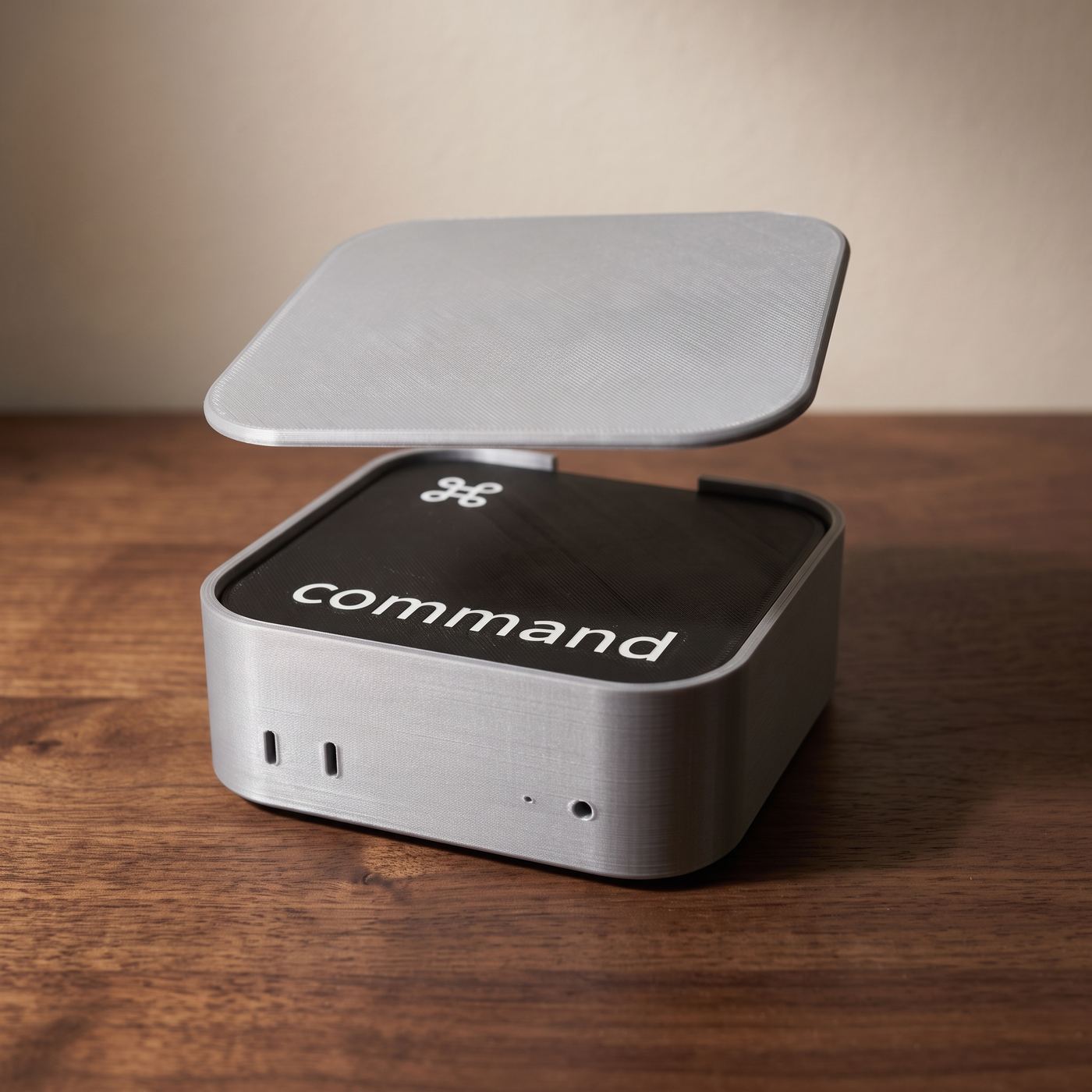 The Mac mini holder on a walnut desk with its cap lifted off and hanging above it, the stack of coasters inside with command on top.